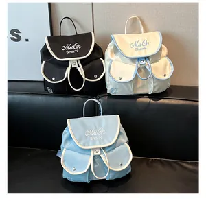 Detailed view of nylon drawstring backpacks in black, beige and blue with bear charm