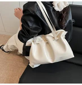 Detail of white pleated tote bag showing glossy textured material and shoulder straps