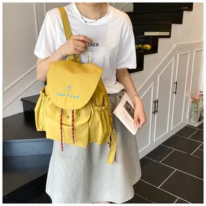 Close-up of a yellow canvas bucket backpack with blue take it easy embroidery details