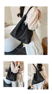 Detail of black woven tote bag with V-shaped texture and spacious hobo shoulder strap design