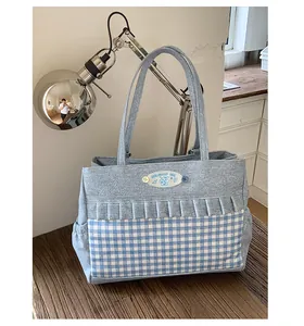 Détail du sac cabas bleu clair avec motif à carreaux et écusson ours mignon