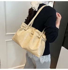 Close-up of cream textured leather tote bag showing pleated details and shoulder strap