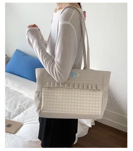Détail du sac cabas en toile avec poche à carreaux à volants et broderie bleue