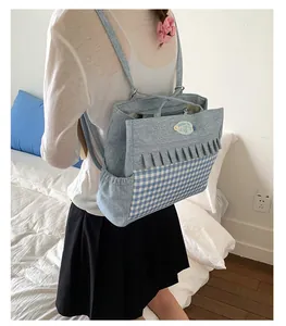 Détail du sac à dos en toile denim bleu clair avec volants à carreaux et logo ours