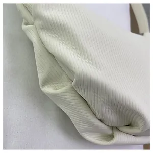 Dettaglio della borsa tote bianco crema con trama a coste verticali e morbide pieghe