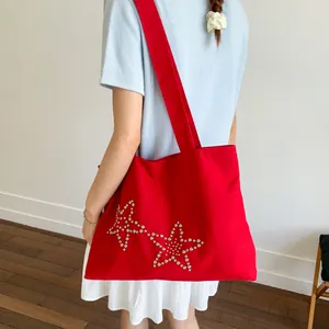 Minimalist red canvas tote bag with silver star rivet details shown on a female model