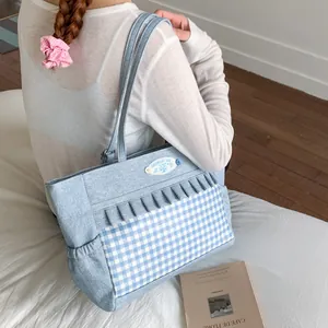 Sac cabas en toile bleu clair avec motif à carreaux et volants porté par un mannequin