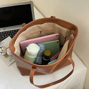 Brown leather tote bag showing large capacity for laptop, water bottle, and accessories