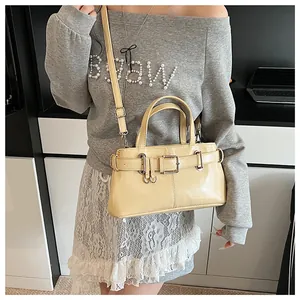 Dettaglio di una borsa crema chic con cinturini decorativi e fibbie in metallo lucido