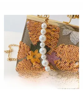 Detail of sequin flower shell bag with pearl handle and golden clasp closure