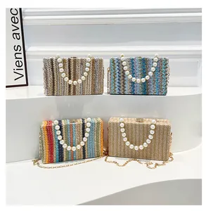 Detail of woven straw box bags featuring pearl handles and elegant gold chain straps
