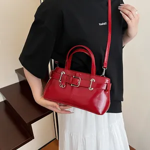 Borsa sottobraccio rossa lucida stile moto con fibbie decorative indossata dalla modella
