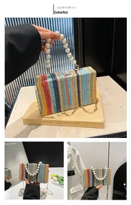 Detail of multicolor woven crossbody bag with elegant faux pearl handle and gold chain strap