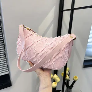 Pink crescent underarm bag with frayed denim tassels and quilted texture in summer style