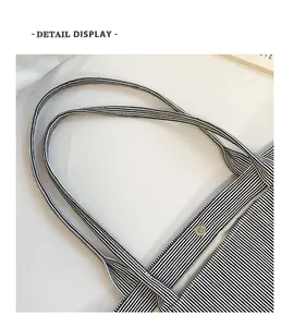 Detail view of the black and white striped canvas tote with a metal snap button closure