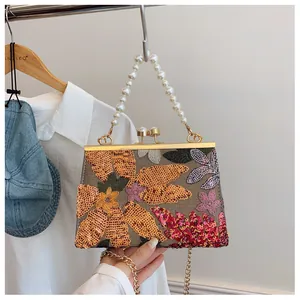 Detailed close-up of handmade sequin floral embroidery and elegant pearl handle on bag