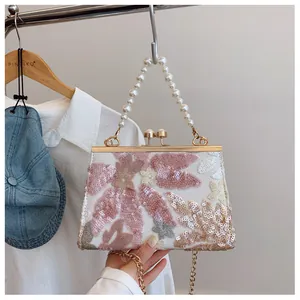 Detail of sequin flower embroidery on ivory shell bag with pearl handle and metal clasp