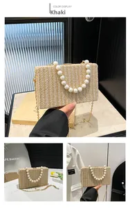 Detail of straw woven bag featuring large white pearl handle and golden chain strap