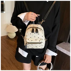 Detail eines cremefarbenen Mini-Rucksacks mit Faltenstruktur und schwarzen Schleifen