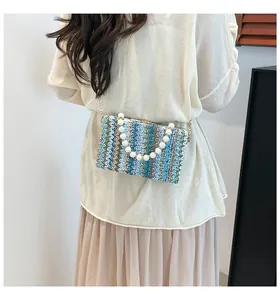 Detail of colorful woven straw handbag with large pearl handle and metal chain strap
