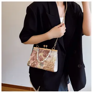 Detail of sequin floral embroidery and pearl handle on a retro shell-shaped evening bag