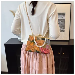 Detailed view of floral sequin shell bag with pearl handle and golden chain strap