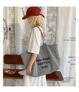 Detail of canvas tote bag with gray stripes and Make Magic Happen slogan print
