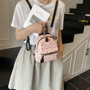 Rosafarbener Mini-Rucksack mit Plissee-Struktur, schwarzen Schleifen und Träger am Model