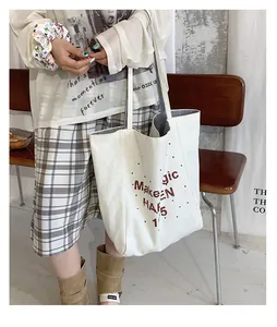 Detail of canvas tote bag with brown artistic lettering and black-white striped lining