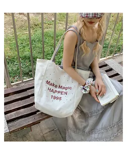 Close-up of white canvas tote bag with 'Make Magic HAPPEN 1995' text print and vintage style