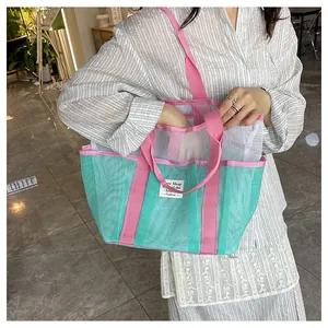 Detail of mint green and pink mesh tote bag with side pockets and woven label