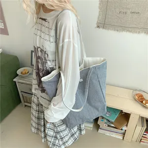 Large blue and white striped canvas tote bag with white handles carried by a model