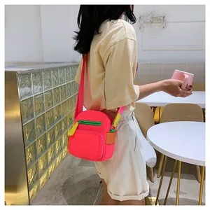 Close-up of a pink nylon crossbody bag with contrasting zipper details on a model