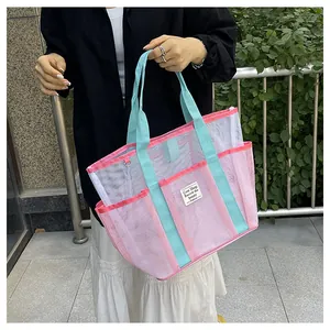 Detail of pink and white mesh tote bag with blue handles and exterior storage pocket