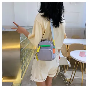 Detail of grey mini oxford bag with neon green and orange zippers on a female model