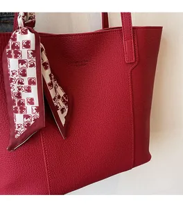Detailed macro view of red lychee grain leather tote bag with silk scarf decoration
