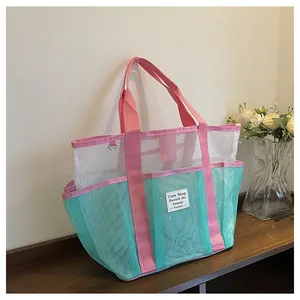 Close-up of a multi-pocket mesh tote bag with pink straps on a wooden shelf