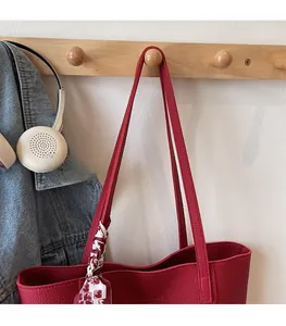 Detail of red leather tote bag with silk scarf and comfortable shoulder strap design