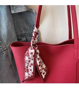Detail of red leather tote bag with lychee texture and decorative floral silk scarf