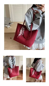 Close-up of red lychee leather tote bag with stylish silk scarf detail on handle