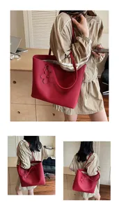 Detail of red leather tote bag showing textured surface and elegant flower pendant