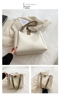 Detail view of white minimalist tote bag featuring brown leather handles and metal chain buckle