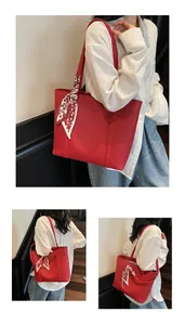 Detail of red leather tote bag with silk scarf handle and embossed logo text
