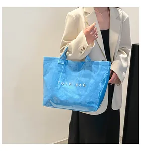 Gros plan du sac cabas en PVC bleu brillant avec lettrage blanc TOTE BAG