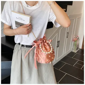 Dettaglio borsa a secchiello in raso rosa con decorazioni in perle e tracolla a catena