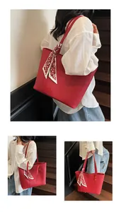 Detail of red pebbled leather tote bag with decorative silk scarf and handle close-up