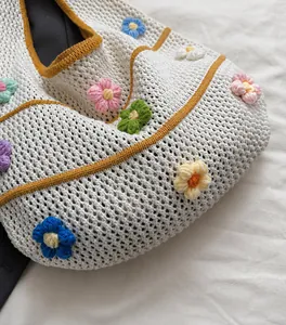 Nahaufnahme der cremefarbenen Häkeltasche mit bunten gestrickten 3D-Blumen und Textur