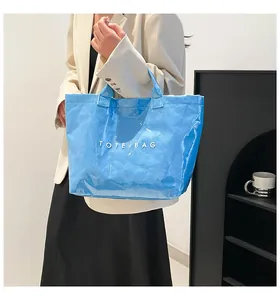 Détail du cabas en PVC bleu ciel brillant avec texte TOTE BAG blanc et texture plissée