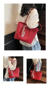 Detail of red tote bag with lychee texture, chic printed scarf handle and brand logo