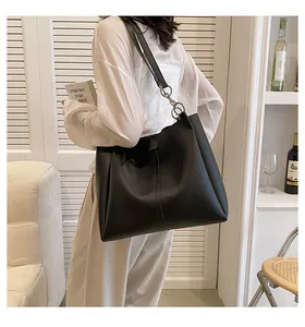 Detail of black matte leather tote bag featuring large silver metal rings and vertical stitching